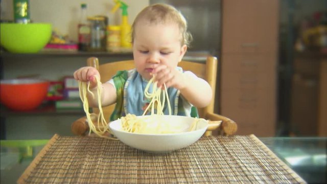 Funny child playing with spaghetti and sauce. Scene 1