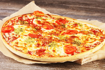 Hot true ITALIAN PIZZA with basil and cheese. TOP VIEW Tasty traditional pepperoni pizza on board on wooden table with decoration