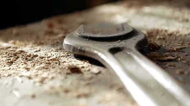 Close up footage of spanner lying on tabel covered with wooden sawdust in joinery