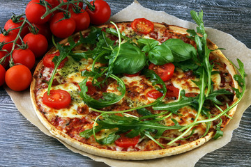 Hot true ITALIAN PIZZA with basil, arugula and cheese. TOP VIEW Tasty traditional pepperoni pizza on board on wooden table with decoration