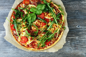 Hot true ITALIAN PIZZA with basil, arugula and cheese. TOP VIEW Tasty traditional pepperoni pizza on board on wooden table with decoration