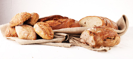 Different kinds of bread and bread rolls on board from above. Kitchen or bakery poster design.