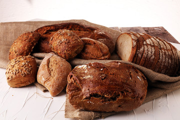 Different kinds of bread and bread rolls on board from above. Kitchen or bakery poster design.