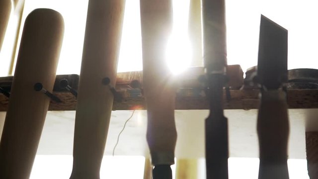 Close up footage in slowmotion with sun flare. Hand tools for wood work hanging on handmade rack in joinery