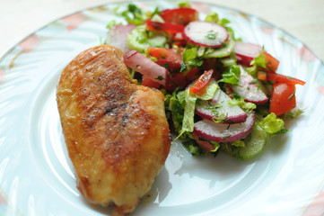 Baked chicken breast with vegetable salad on a white plate