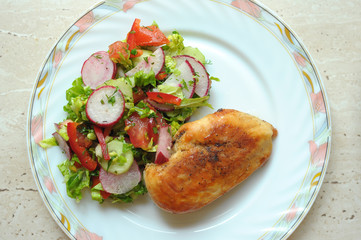 Baked chicken breast with vegetable salad on a white plate