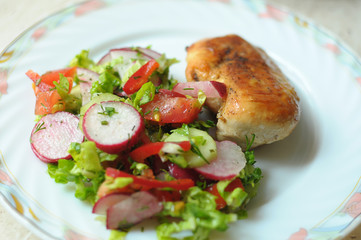Baked chicken breast with vegetable salad on a white plate