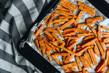 Baked sweet potatoes fries on black backing plate