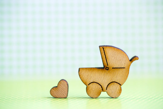 Wooden icon of baby buggy and little heart on green checkered background