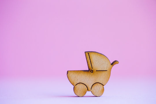Wooden icon of baby buggy on pink background