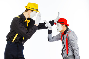 Two young men, an actor, a MIME, in clothing and makeup, argue, and gesticulate on a white background.