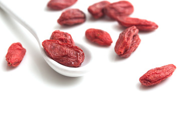 Baies de Goji et petite cuillère sur fond blanc