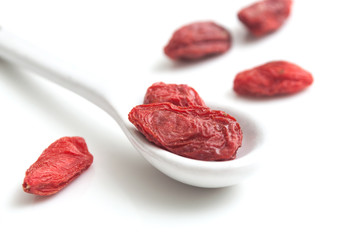 Baies de Goji et petite cuillère sur fond blanc