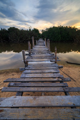 Obraz premium The old wooden bridge over a river at Kg. Pulau Kerengga, Marang Malaysia with sunset scenery