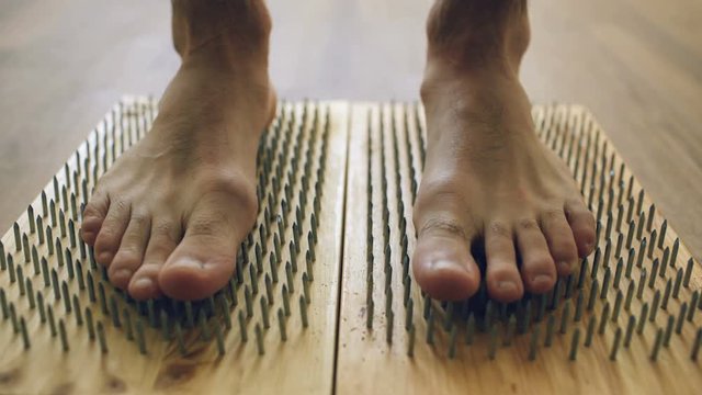 Closeup of yoga man stand on board with sharp nails