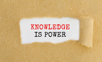 Text Knowledge is power appearing behind ripped brown paper