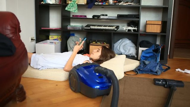A little girl is shirking her homework, playing on her mobile phone. Cleaning of the children's room. Disorder in the teen room
