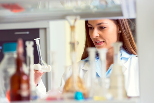 Woman scientist behind lab glassware. Scientist carrying out experiment in research laboratory