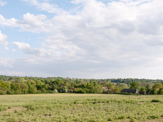 open farmland with houses in the distance outside in the country in essex england dedham in the uk on a bright a sunny day with lots of lush green