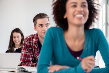 Student smiling while using a tablet during class in a modern college or university