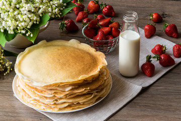 Delicious pancakes on wooden table with strawberries and milk