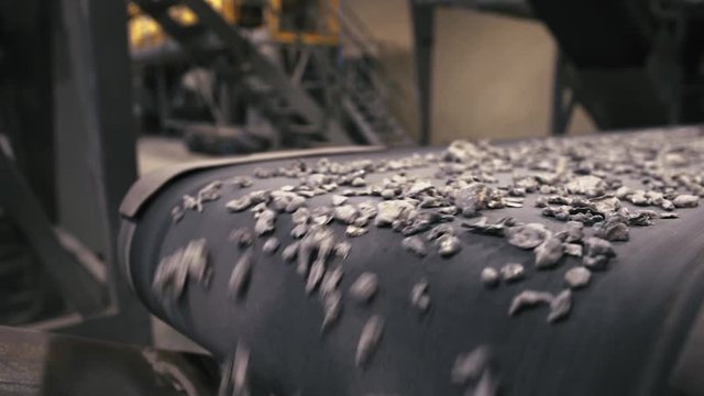 Recycling Facility.  Close-up of assembly line with metal waste on, employee sorting the wasteClose-up of assembly line with metal waste on, employee sorting the waste