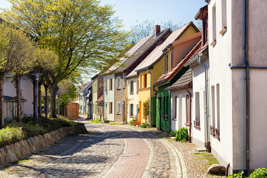 Barth, Germany - April 2017: View down a historic cobble stone street with colourful houses on a sunny day.