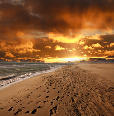 Sandy sea beach with footprints on  dramatic sky