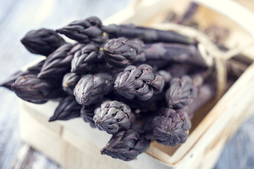 Row purple Asparagus as close-up in a basket