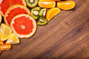 lemon, orange, kiwi, grapefruit, mandarin on a wooden surface. arrangement of sliced fruit. Top view with copy space for text