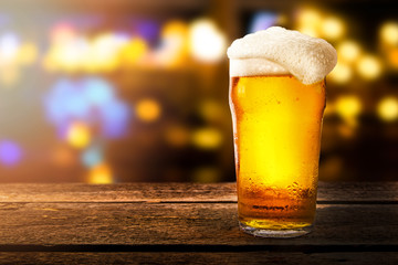 glass of beer on a table in a bar on blurred bokeh background