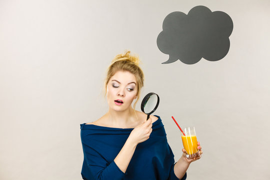 Woman holding magnifying glass investigating juice