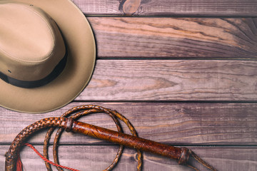 Travel and adventure concept. Vintage fedora hat and bullwhip on wooden table. Top view - obrazy, fototapety, plakaty