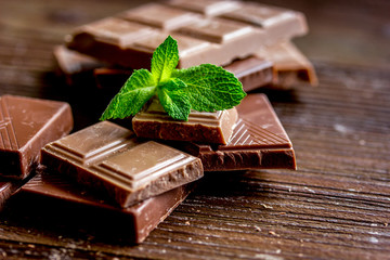black and milk chocolate bars with mint dark wooden table background
