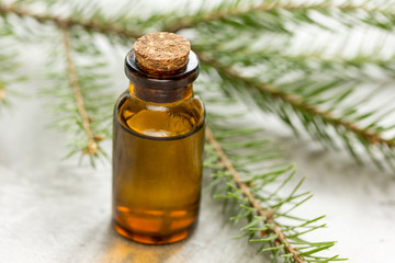cosmetic spruce oil in bottles with fur branches on white table background