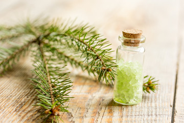 cosmetic spruce salt in bottles with fur branches on wooden table background