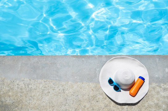 Summer Hat, Sunglasses And Sunscreen Near The Pool