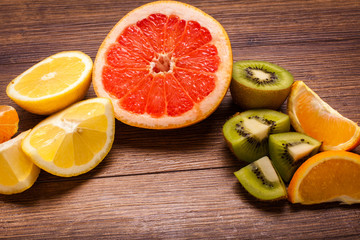Fototapeta na wymiar lemon, orange, kiwi, grapefruit, mandarin on a wooden surface. arrangement of sliced fruit. Top view with copy space for text