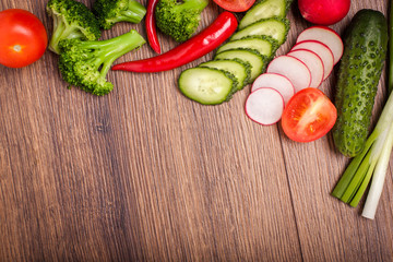 tomato, radish, cucumber, broccoli, onion, chili on a wooden surface. arrangement of sliced vegetables. Top view with copy space for text. Top view with copy space for text