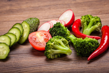 tomato, radish, cucumber and broccoli, chili on a wooden surface. arrangement of sliced vegetables