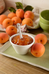 Apricot jam in white bowl with fruit around
