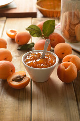 Apricot jam in white bowl with fruit around
