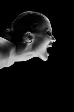 angry nude girl screaming on black background, monochrome
