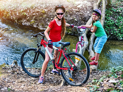 Bicycle teen with ladies bikes in summer park. Womens road bike for running on nature. Teenager girl in helmet cycling fording throught water. Brave children are not afraid to travel unaccompanied.