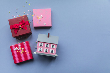 Holidays giftboxes and mini house on the pastel blue background for mortgage offers and money saving with the buying a property