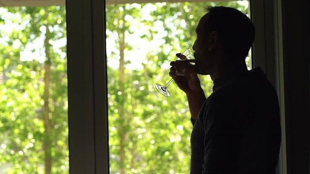 Happy man drinking wine and admire garden view from window, super slow motion 240fps
