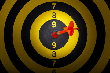 Top view of red arrow in target on yellow dart board