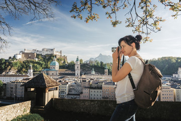 Fototapeta premium Austria. Salzburg. A young tourist girl takes pictures of the historic center of Salzburg UNESCO World Cultural Heritage