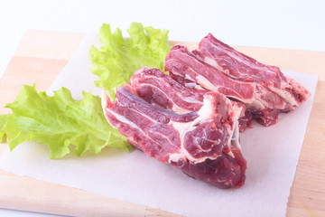 Raw beef edges and lettuce leaf on wooden desk isolated on white background from above and copy space. ready for cooking