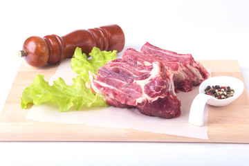 Raw beef edges, lettuce leaf, pepper grinder and spices on wooden desk isolated on white background from above and copy space. ready for cooking.
